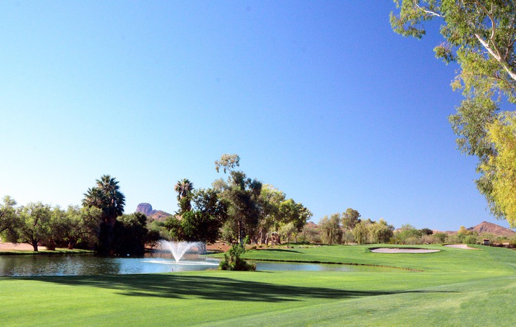 Water fountain and small lake in golf course with view of sand traps