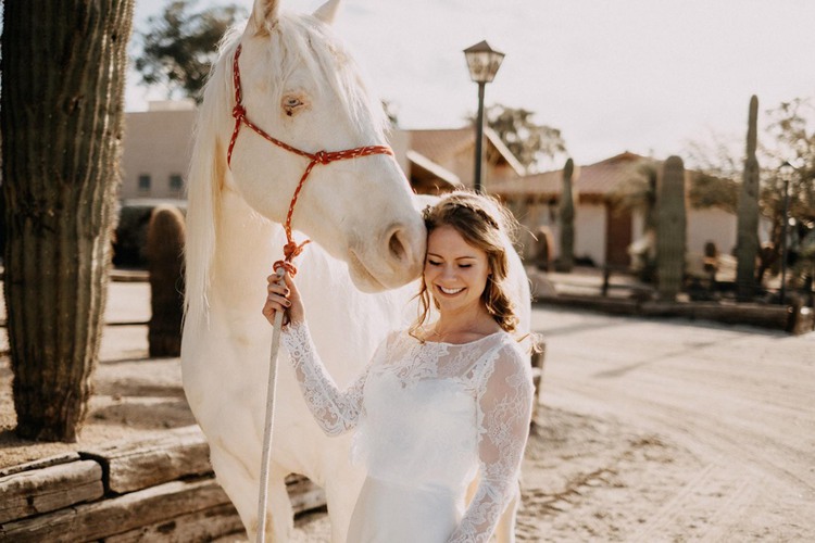 Bride standing next to white horse
