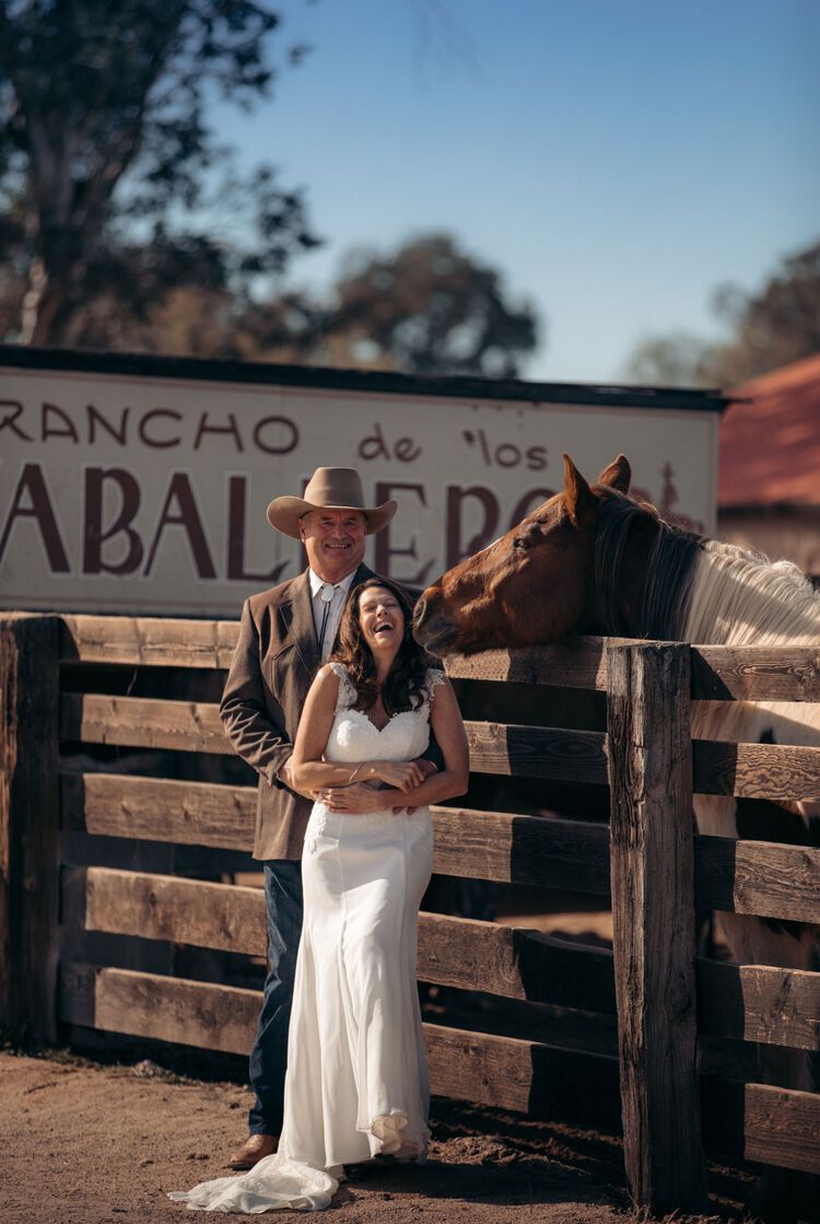 Bride and groom standing beside horse in stable