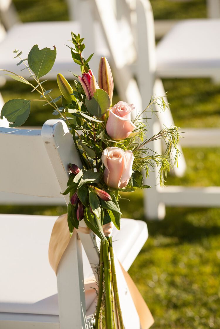 Flowers tied to white wedding chair