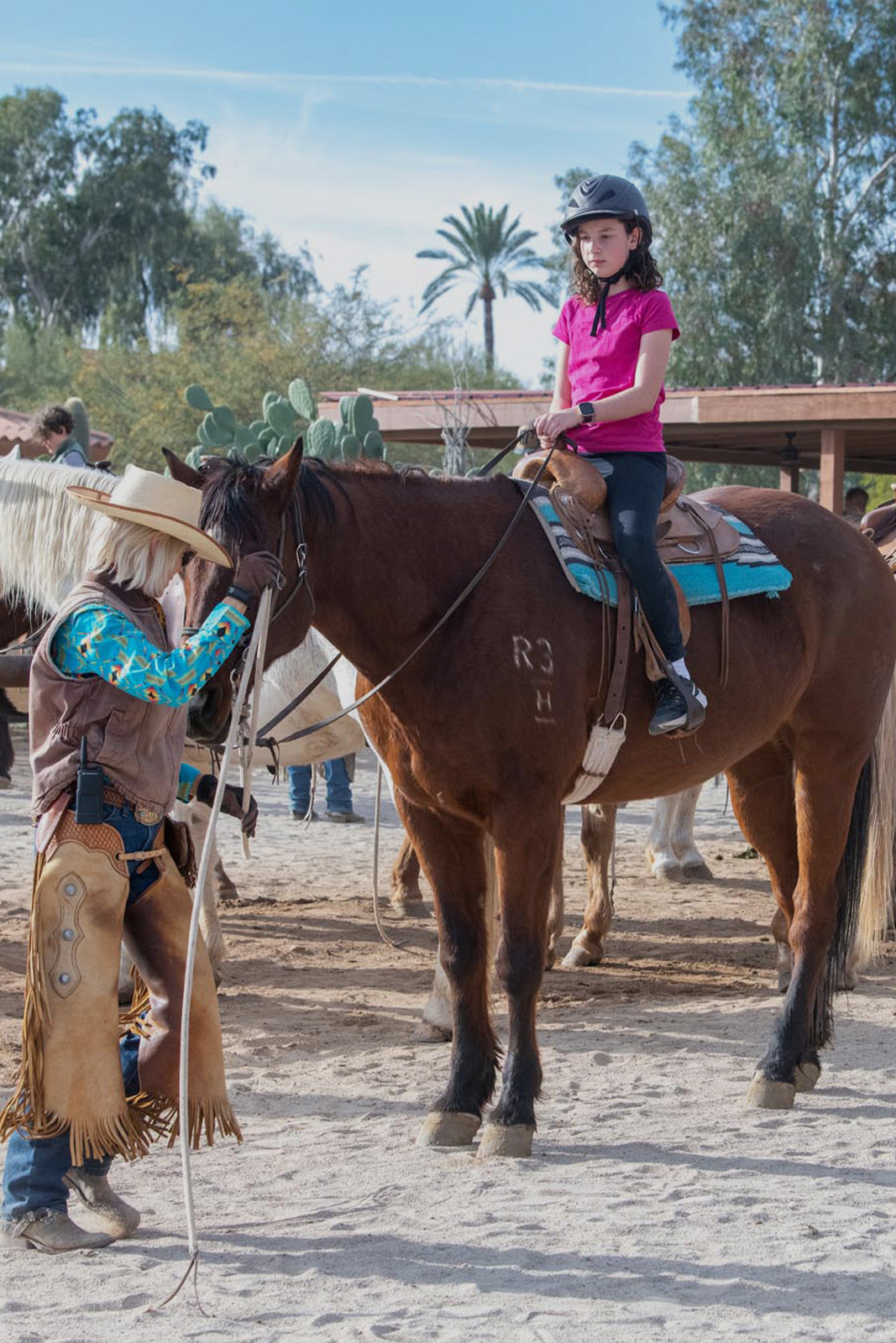 Little girl on horse beside wrangler