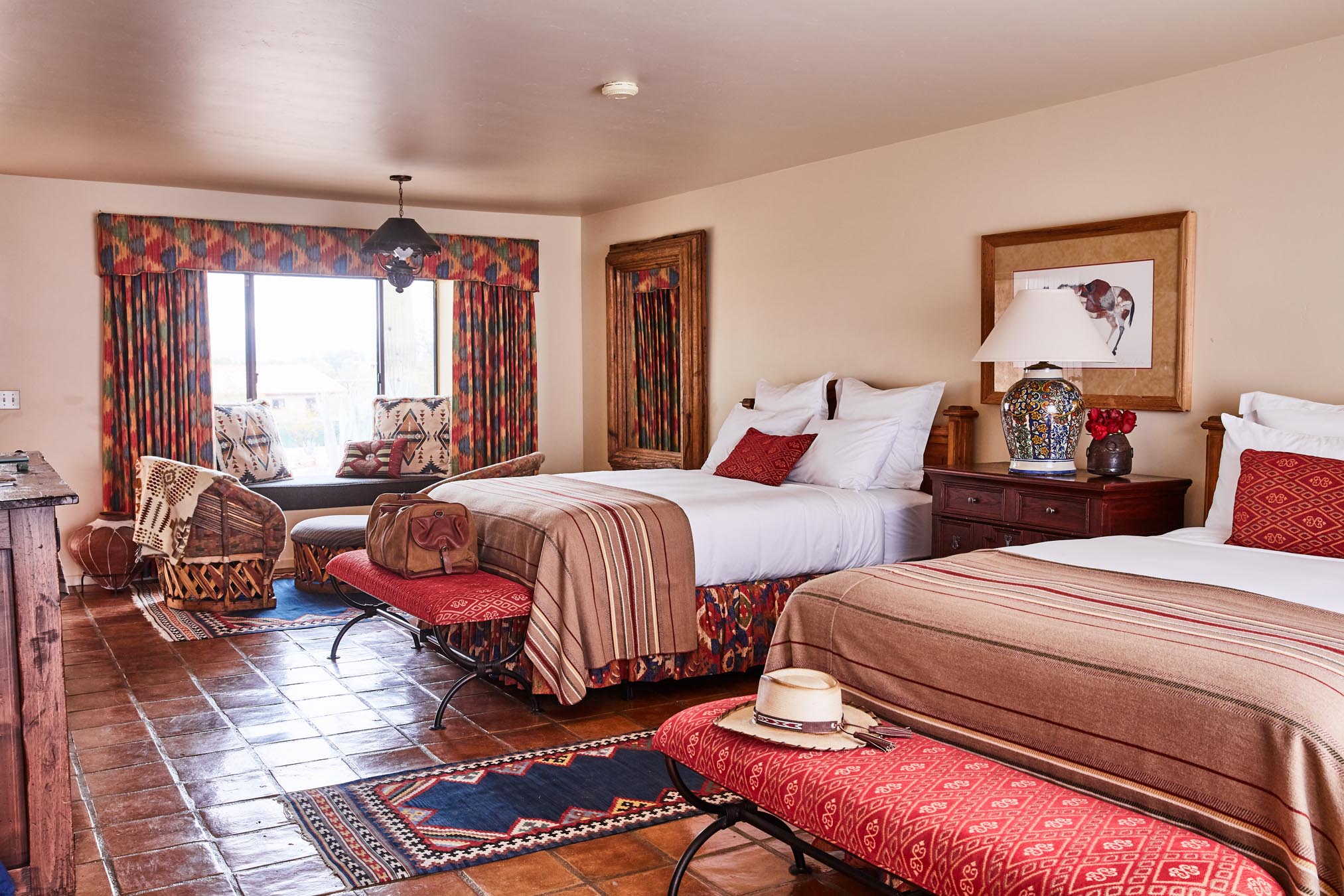 Two queen beds with foot bench with seating area and window seat